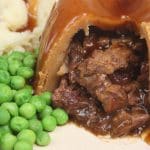 Steamed steak & kidney pudding with suet pastry, peas, mash and gravy.