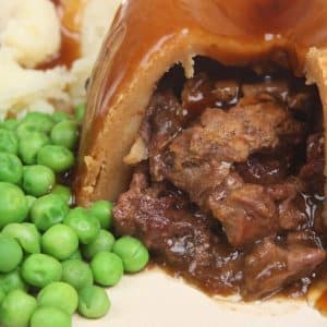 Steamed steak & kidney pudding with suet pastry, peas, mash and gravy.
