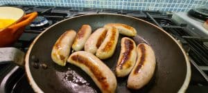 Butchers sausages cooking in the pan