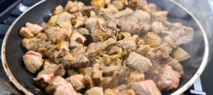 Browning the diced beef and pork