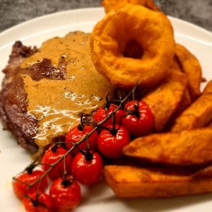 Triple Cooked Chips served with Rib Eye steak, onion rings and tomatoes